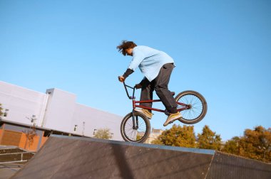 Bmx motorcusu kaykay parkında rampada numara yapıyor.
