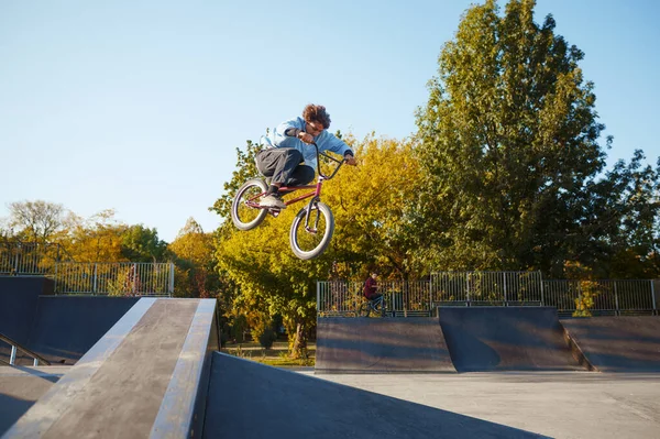 Bmx motorcusu kaykay parkında tırabzan kullanarak gidiyor.