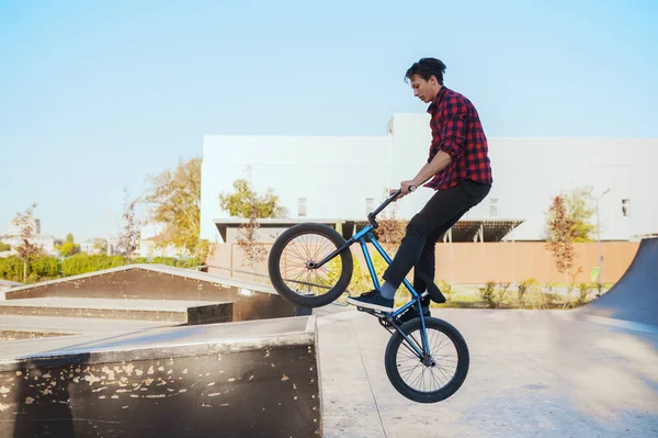 Young bmx biker doing trick, training in skatepark