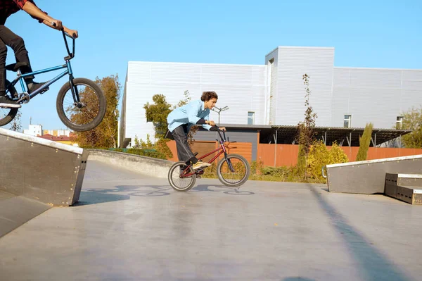 Two male bmx bikers doing tricks in skatepark