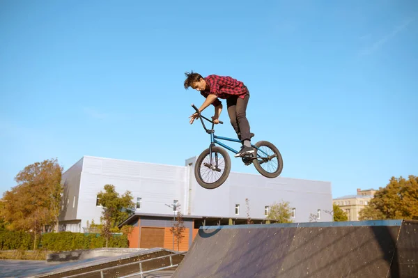 Male bmx biker jumps on ramp in skatepark