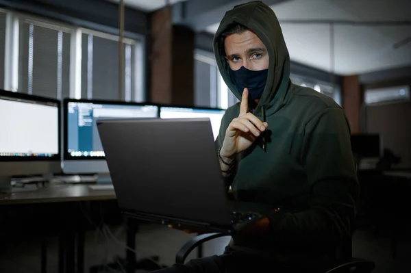 フードの男性のインターネットハッカーは暗いオフィスのラップトップで動作します 職場での違法Webプログラマー 犯罪者の職業 データハッキングサイバーセキュリティ — ストック写真