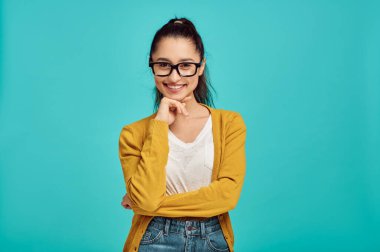 Gözlüklü gülümseyen kadın, mavi arka plan, olumlu duygu. Yüz ifadesi, stüdyoda kameraya bakan kadın, duygusal konsept, duygular.