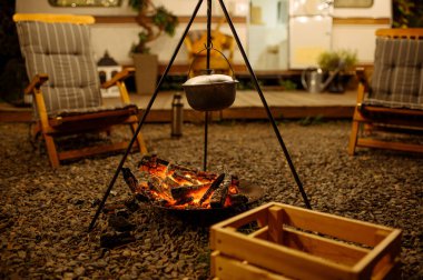 Esrar kamp ateşinin üstünde, ormanda piknik yapıyorlar, kimse yok. Karavanda yaz macerası, arka planda kamp arabası. Karavanla seyahat etmek, şenlik ateşiyle yemek pişirmek.