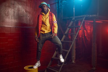 Süslü rapçi, grunge stüdyosunun merdivenlerinde havalı yeraltı dekorasyonuyla poz veriyor. Hip-hop sanatçısı, rap şarkıcısı, break-dans