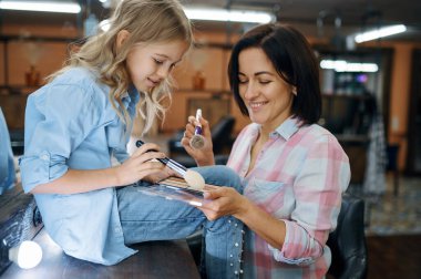 Anne ve kızı makyaj salonunda toz kullanıyorlar. Anne ve küçük kız birlikte oyun stilistleri, mutlu çocukluk, büyüleyici aile.