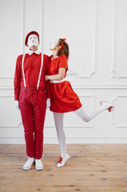 Kırmızı kostümlü iki pandomimci, öpüşme sahnesi. Pandomim tiyatrosu, parodi komedyeni, olumlu duygu, mizah performansı, komik yüz taklidi ve asık surat.