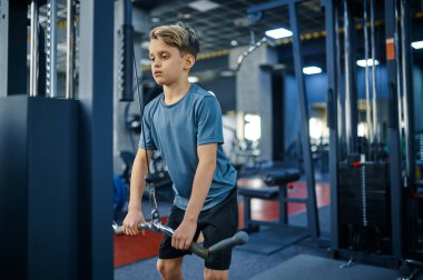 Egzersiz makinesinde bir çocuk, spor salonunda aktif eğitim. Spor kulübündeki gençler, sağlık hizmetleri ve sağlıklı yaşam tarzı, spor yapan okul çocuğu, sportif gençlik.