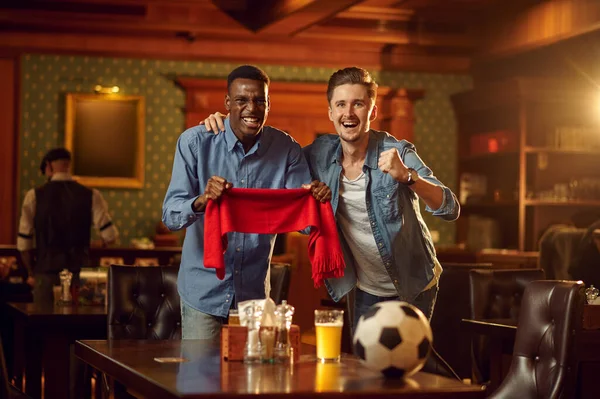 赤いスカーフとボールゲームテレビ放送を見ている2人の男性サッカーファン バーの友人 パブでリラックスした人々のグループ ナイトライフ スポーツ勝利のお祝い — ストック写真
