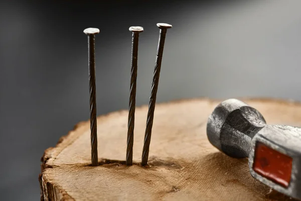 Screw nails and hammer on stump, grey background — Stock Photo, Image