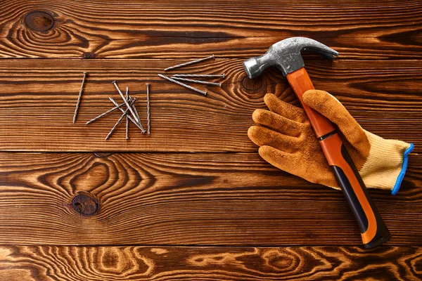 Screw nails, hammer and glove on wooden background — Stock Photo, Image