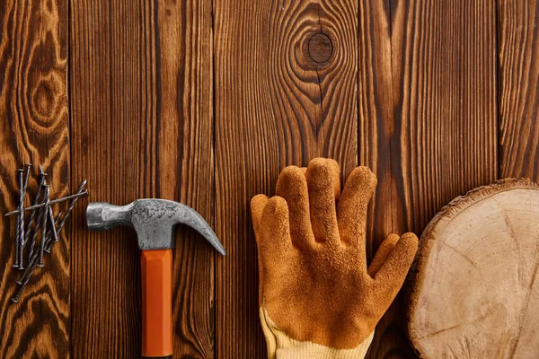 Šroub hřebíky, kladivo a rukavice na dřevěném pozadí — Stock fotografie