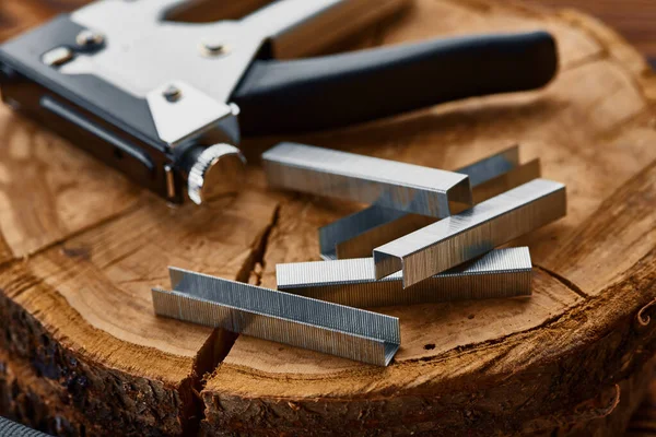 Metal stapler and steel staples on stump, macro — Stock Photo, Image