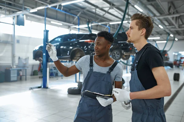 两名男性机械师在汽车服务方面的谈话 修车厂 穿制服的人 车厂内部背景 专业自动诊断 — 图库照片