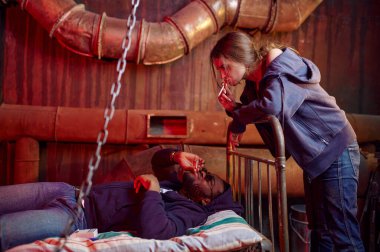 Uyuşturucu bağımlıları sigara içerken arka planda terk edilmiş bir ev. Uyuşturucu bağımlılığı sorunu, bağımlı insanların sonsuz depresyonu.