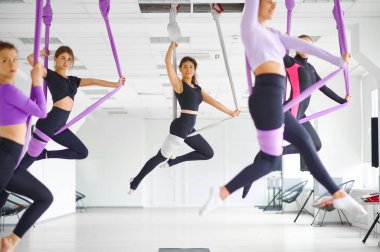 Yoga dersi, kadın grup eğitimi, hamaklarda asılı kalma. Fitness, pilates ve dans egzersizleri karışımı. Kadınlar spor stüdyosunda yoga yapıyor.