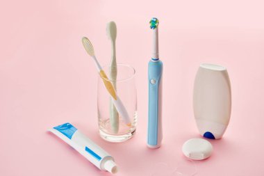 Ağız bakım ürünleri, diş fırçaları, diş macunu, diş ipi, pembe arka plan, hiç kimse. Sabah sağlık prosedürleri kavramı