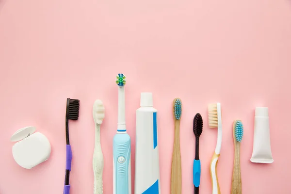 口腔保健产品粉色背景没人上午保健程序的概念 牙齿护理 不同的牙刷和牙膏 刷子和奶油在瓶子里 — 图库照片