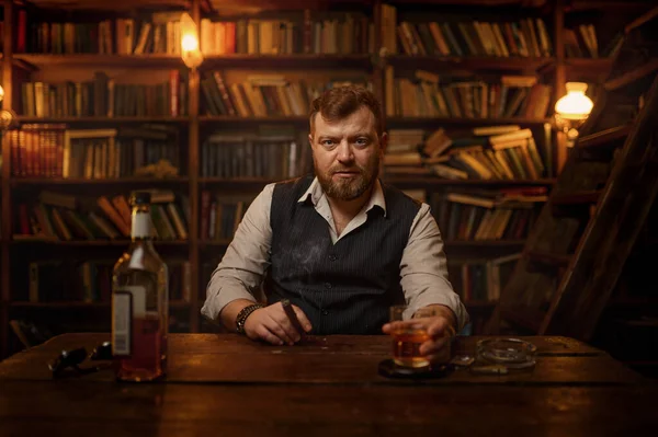 Focused man sipping alcoholic beverage while thinking about next chess move.  Stock Photo by DC_Studio