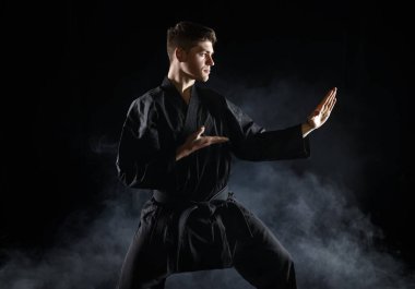 Siyah kimonolu erkek karate dövüşçüsü, dövüş duruşu, karanlık bir geçmişi var. Antrenman yapan adam, dövüş sanatları, dövüş yarışması