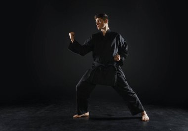 Siyah kimonolu erkek karate dövüşçüsü, dövüş duruşu, karanlık bir geçmişi var. Antrenmanlı adam, dövüş sanatları.