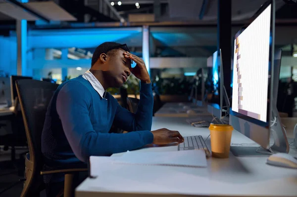 经理睡在餐桌前 上夜班 手提电脑上的男性 背景深色 现代工作场所 — 图库照片