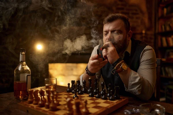 Man Smokes Cigar Drinks Alcohol Beverage Play Chess Bookshelf Vintage — Stock Photo, Image