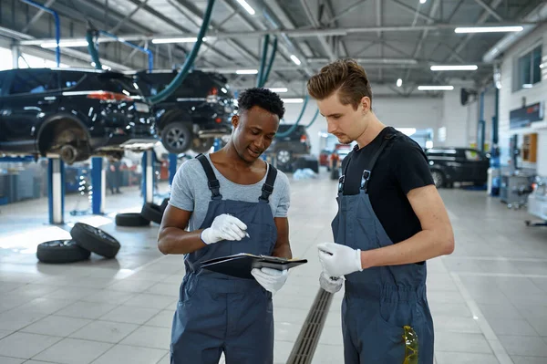 两名男性机械师在汽车服务方面的谈话 修车厂 穿制服的人 车厂内部背景 专业自动诊断 — 图库照片