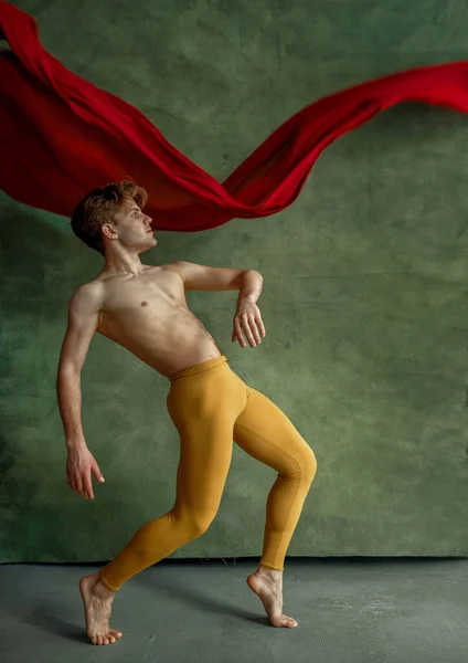 男性バレエダンサーがダンススタジオ グランジウォール 赤い布を背景に運動をしています 筋肉のボディ 優雅さと動きの優雅さとパフォーマー — ストック写真