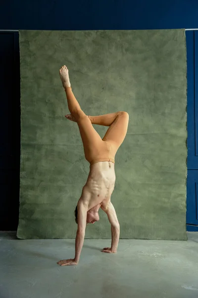 男性バレエダンサーが手に立ち 背景にはグランジウォール ダンススタジオ 筋肉質の身体 優雅さと動きの優雅さを持つダンスパフォーマー — ストック写真