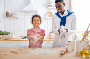 Mutlu baba-kız kahvaltıda kek pişiriyor. Gülümseyen aile sabahları mutfakta yemek yer. Babası kadın çocuğu besliyor, iyi bir ilişki.