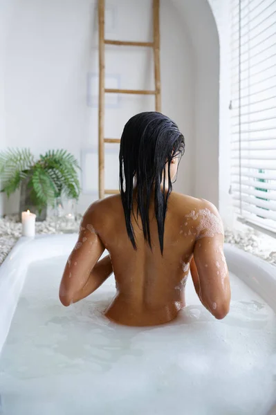 매력적 인 여자가 거품 목욕을 하고 뒤를 돌아보며 긴장을 풀다 — 스톡 사진