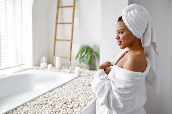 Attraktiv kvinna i badrock sitter nära badkaret — Stockfoto