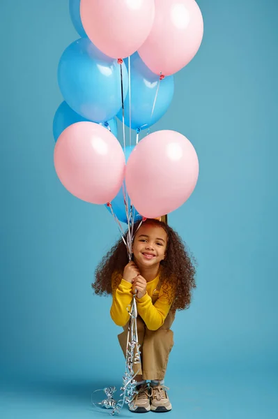 Забавная маленькая девочка в кепке держит кучу шариков — стоковое фото