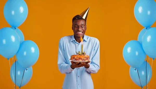 Man in cap holding birthday cake with firework