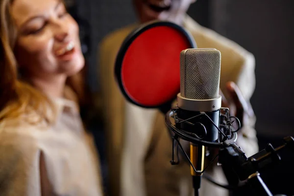 戴耳机的男歌手和女歌手在麦克风边唱歌 背景是录音室的内部 专业语音记录 音乐家工作场所 创作过程 现代音频技术 — 图库照片