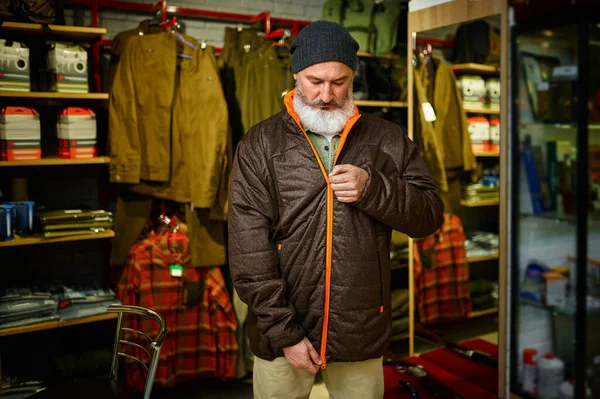 Sakallı avcı silah dükkanında ceketini deniyor. — Stok fotoğraf