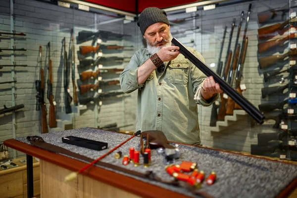 Cazador de hombres barbudos eligiendo baqueta en la tienda de armas —  Fotos de Stock