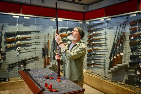Cazador barbudo comprando rifle de caza en la tienda de armas —  Fotos de Stock