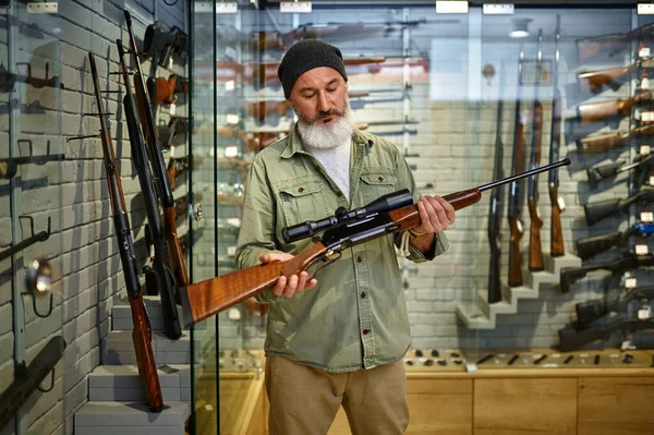 Hunter sostiene rifle con mira óptica en la tienda de armas —  Fotos de Stock