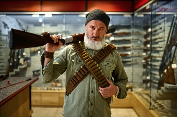 Homme chasseur avec fusil et bandoliers dans un magasin d'armes à feu — Photo