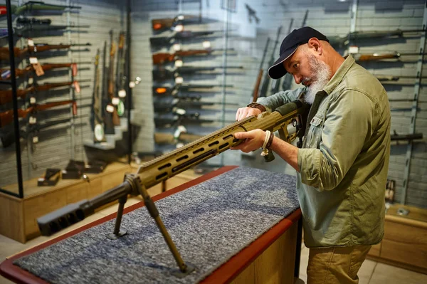 Hombre barbudo recarga rifle de gran alcance en la tienda de armas —  Fotos de Stock