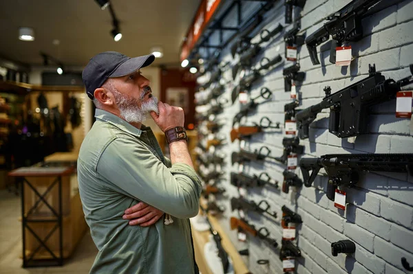 Vendedor masculino em vitrine com rifles na loja de armas — Fotografia de Stock