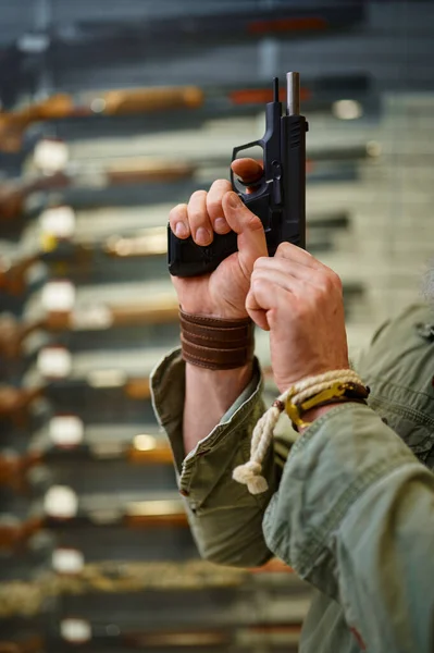 De man met de baard trekt de pistoolgrendel in de wapenwinkel. — Stockfoto