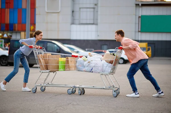 Paar met tassen in karren grappen over parkeren — Stockfoto