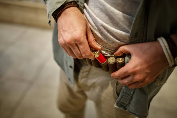 Male hunter loads leather bandolier in gun store — Fotografia de Stock