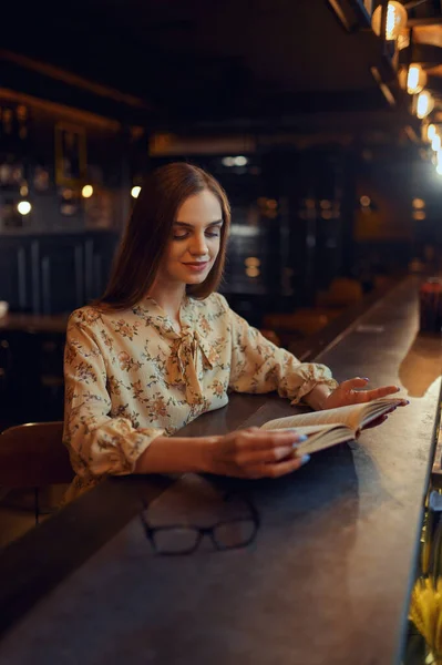 Женщина с книгой сидит за стойкой в баре — стоковое фото