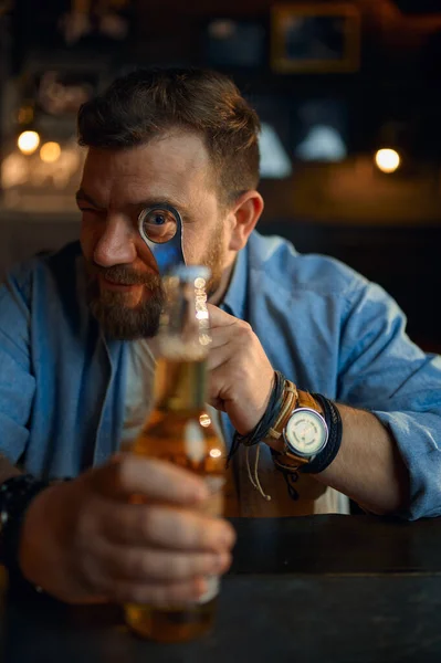 Homem com garrafa de cerveja sentado no balcão no bar — Fotografia de Stock