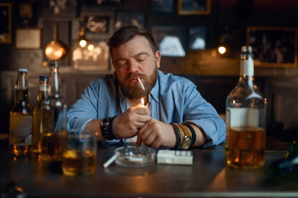 Drunk man smokes a cigarette at the counter in bar — Fotografia de Stock