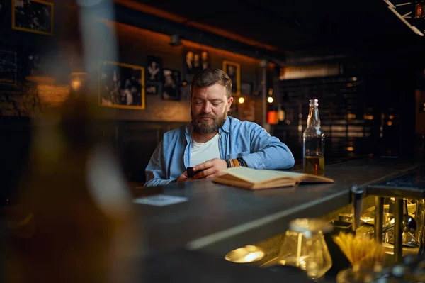 A férfi mobiltelefont használ a pultnál a bárban — Stock Fotó